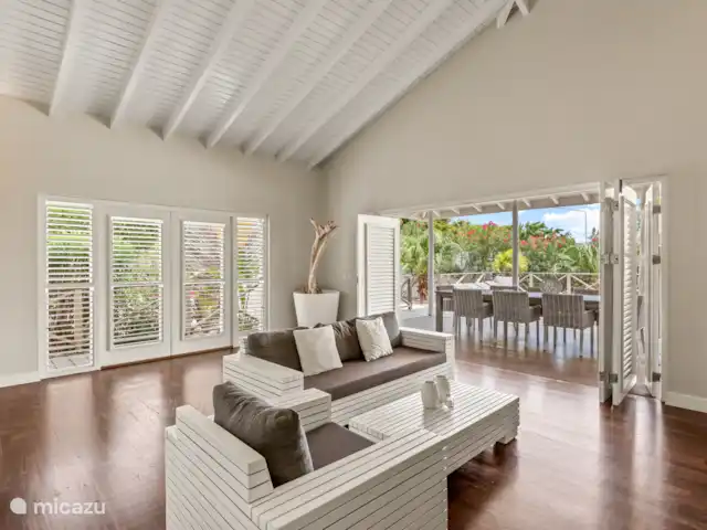 Villa Solaya 1, Jan Thiel | Curaçao, Banda Ariba (est), Jan Thiel - villa Salon tropical avec hauts plafonds, portes-fenêtres et cuisine ouverte. La maison vous donne la vraie sensation d’intérieur-extérieur.