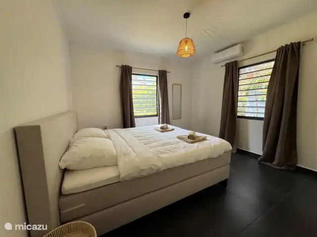 Location de Vacances Curaçao, Banda Ariba (est), Jan Thiel, maison de vacances - Casita Apapacho Puru Jan Thiel  Grande chambre avec lit boxspring king-size de haute qualité (180x200) avec une couette (240x210), des tables de chevet, un miroir, un panier à linge, un placard avec pendre et poser et un coffre-fort.