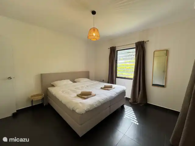 Location de Vacances Curaçao, Banda Ariba (est), Jan Thiel, maison de vacances - Casita Apapacho Puru Jan Thiel  Grande chambre avec lit boxspring king-size de haute qualité (180x200) avec une couette (240x210), climatisation, tables de chevet, miroir, panier à linge, placard avec penderie et pose et un coffre-fort.