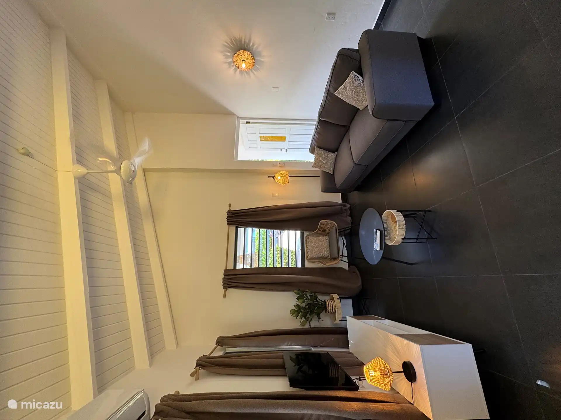 Salon avec canapé 3 personnes, fauteuil, télévision connectée, ventilateur de plafond et climatisation. 