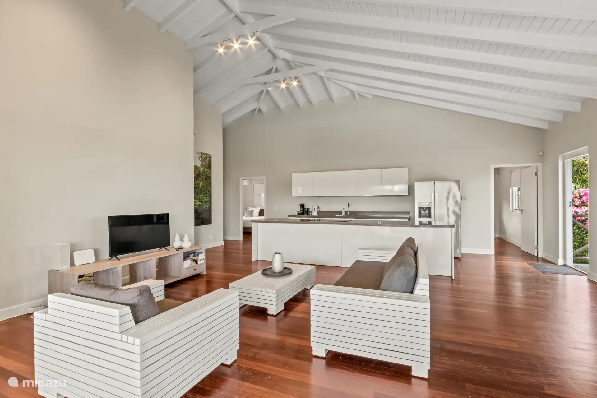 Geräumiges Wohnzimmer mit hohen Decken, gemütlicher Sitzecke und offener Küche