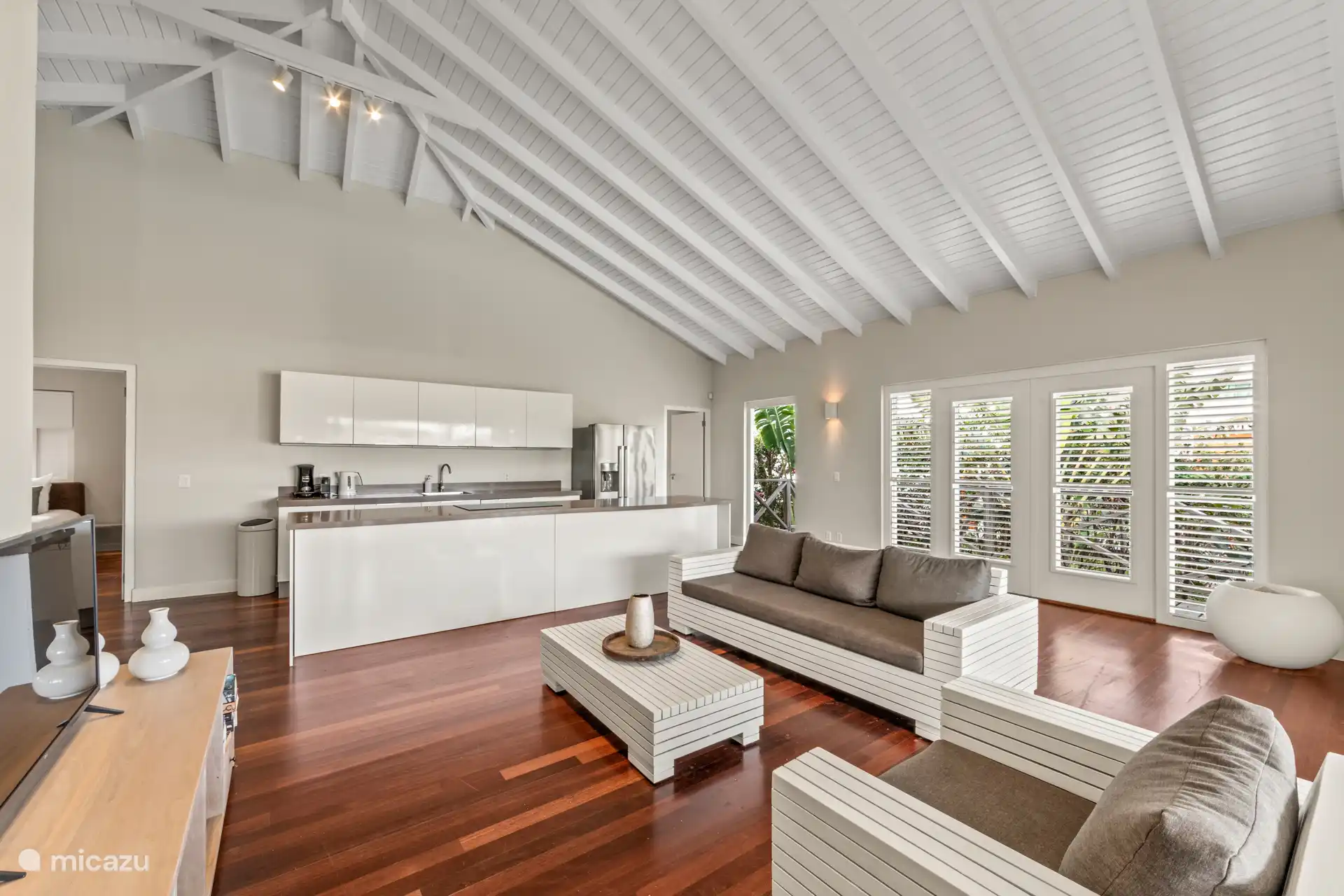 Geräumiges Wohnzimmer mit hohen Decken, gemütlicher Sitzecke und offener Küche