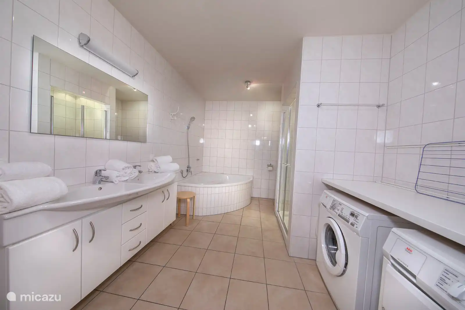 Badkamer 1 met dubbele wastafel, douche, bad, toilet, wasmachine en droger.