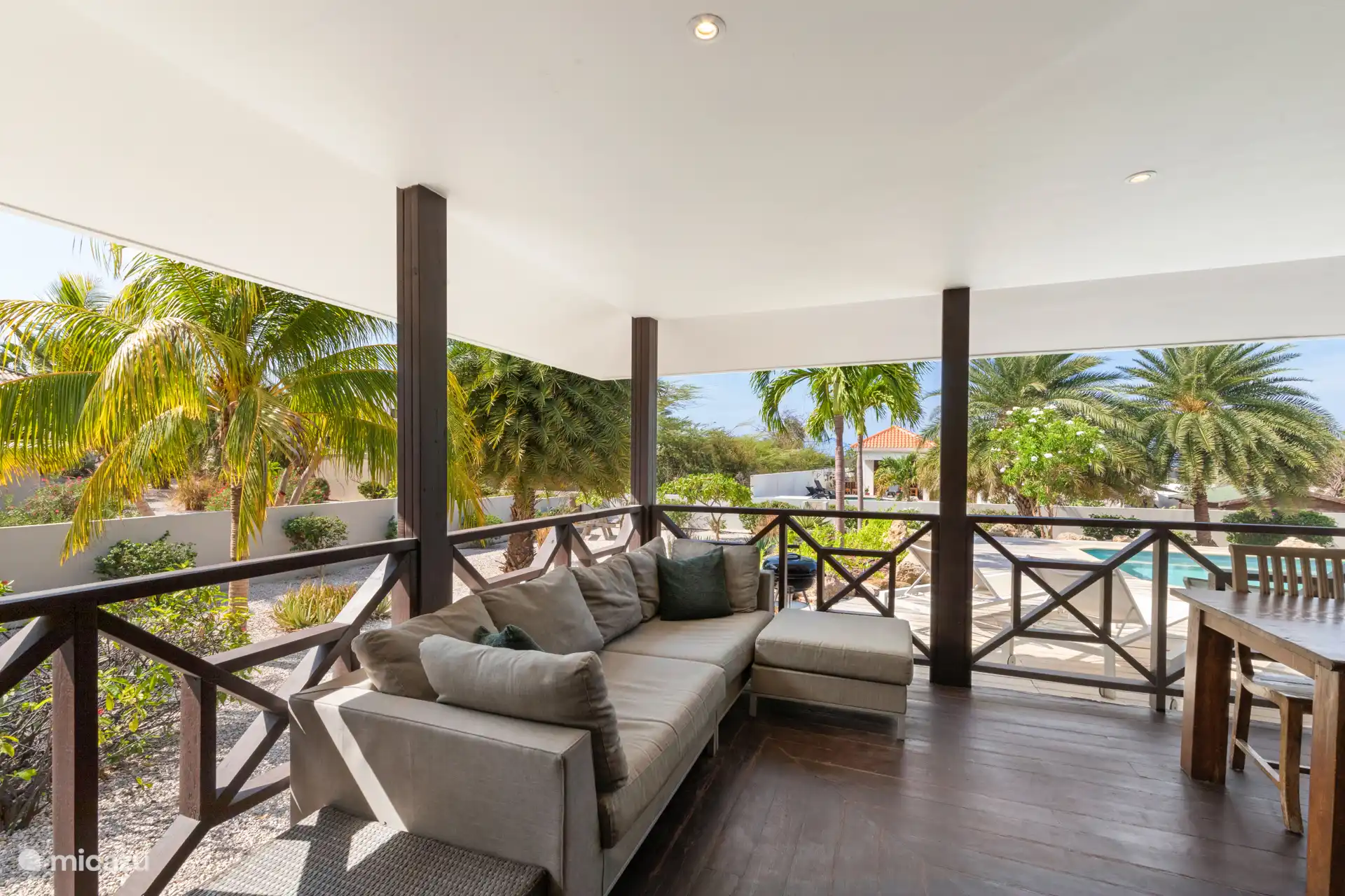 Lounge auf der überdachten Terrasse mit Blick auf den Garten und den privaten Pool.