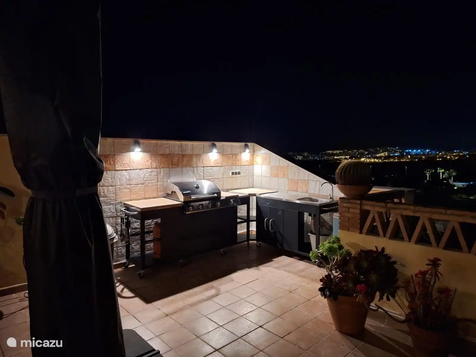 Terraza en la azotea atractivamente iluminada con cocina al aire libre por la noche