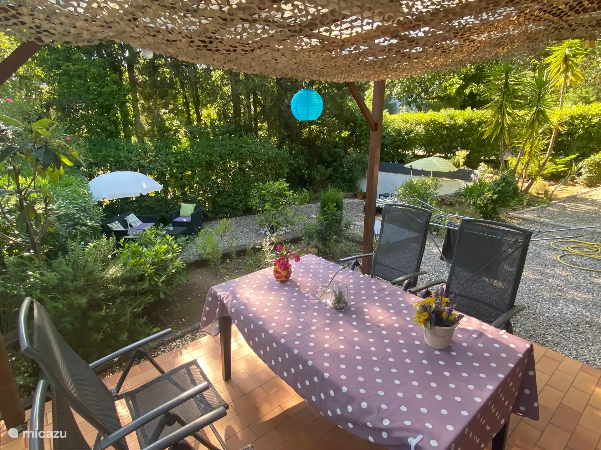 Von der Veranda aus blickt man auf die Lounge-Grube mit Lounge-Set, Hängematte und Sonnenliegen