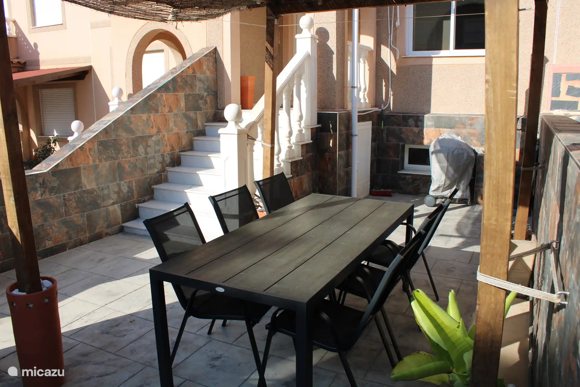 The terrace at the front with pergola, dining table, bbq and separate parasol. 