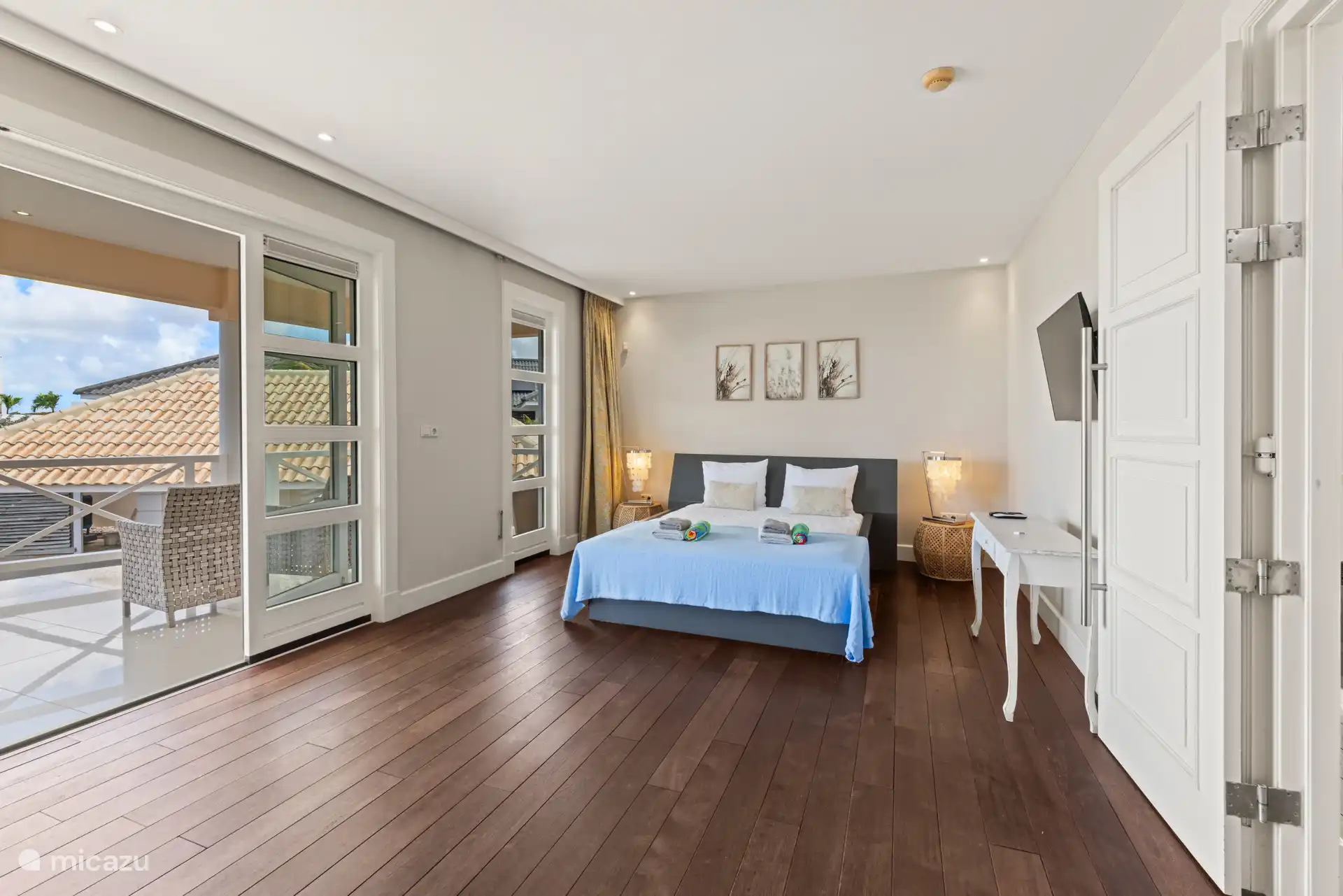 Hauptschlafzimmer mit TV, eigenem Balkon, Bad und begehbarem Kleiderschrank.