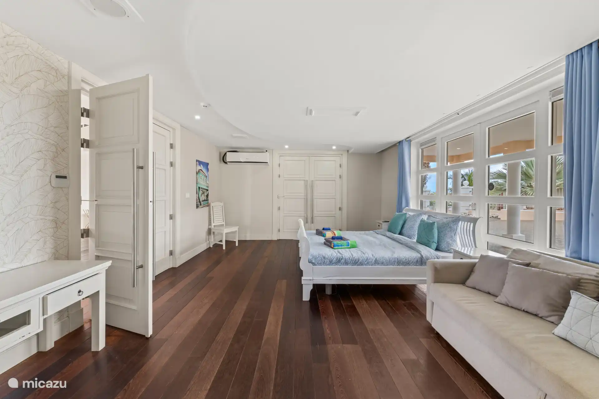 Schlafzimmer im Erdgeschoss mit TV, begehbaren Kleiderschränken und Sofasofa.