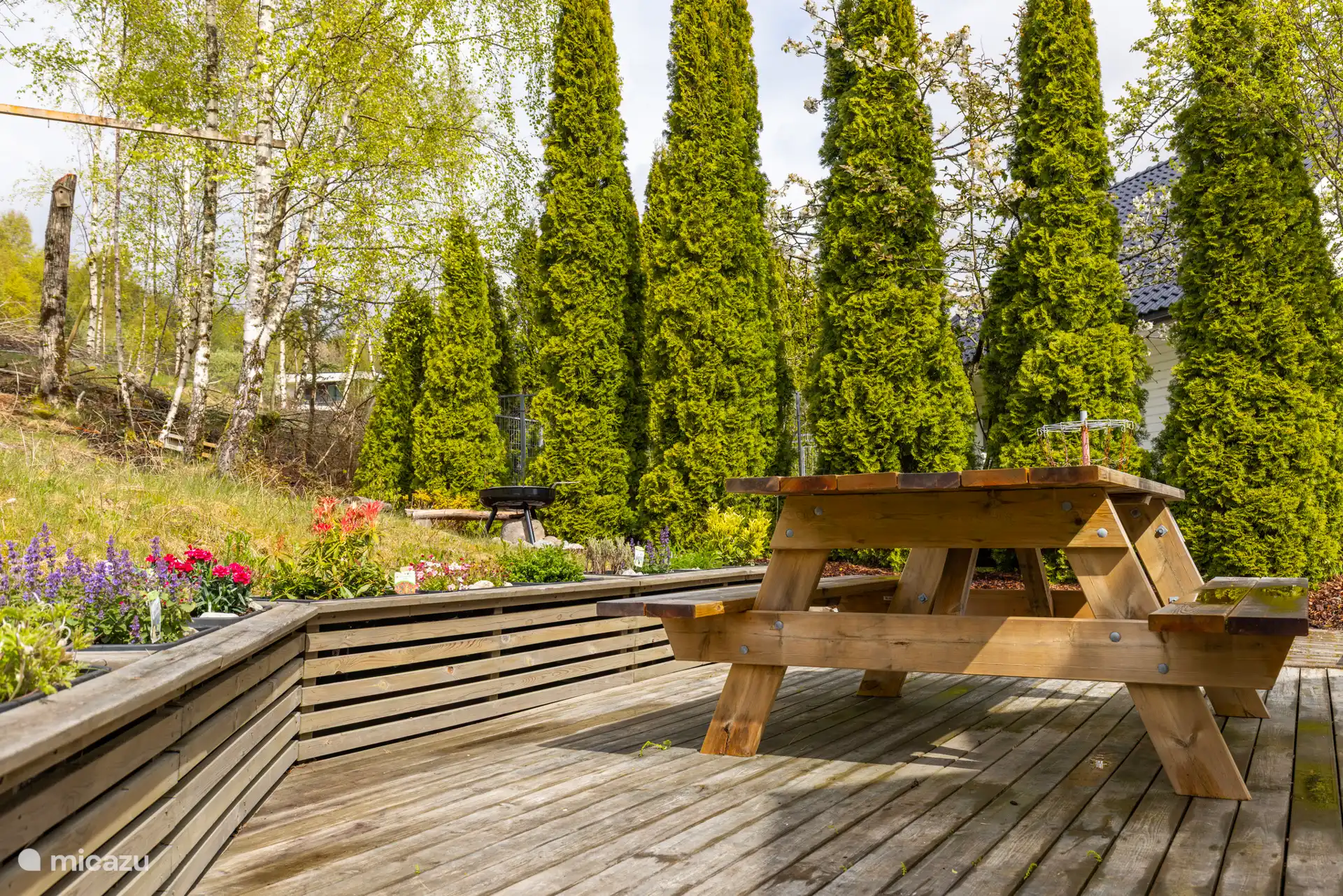 Le jardin privé derrière l’appartement comprend une terrasse avec un coin salon, un barbecue, un bac à sable et un panier à frisbee. 
