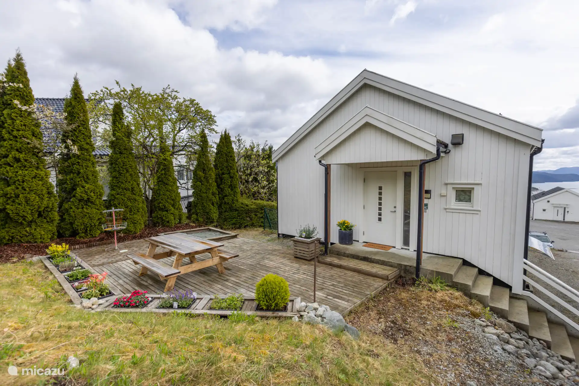 Le jardin privé derrière l’appartement comprend une terrasse avec un coin salon, un barbecue, un bac à sable et un panier à frisbee. 