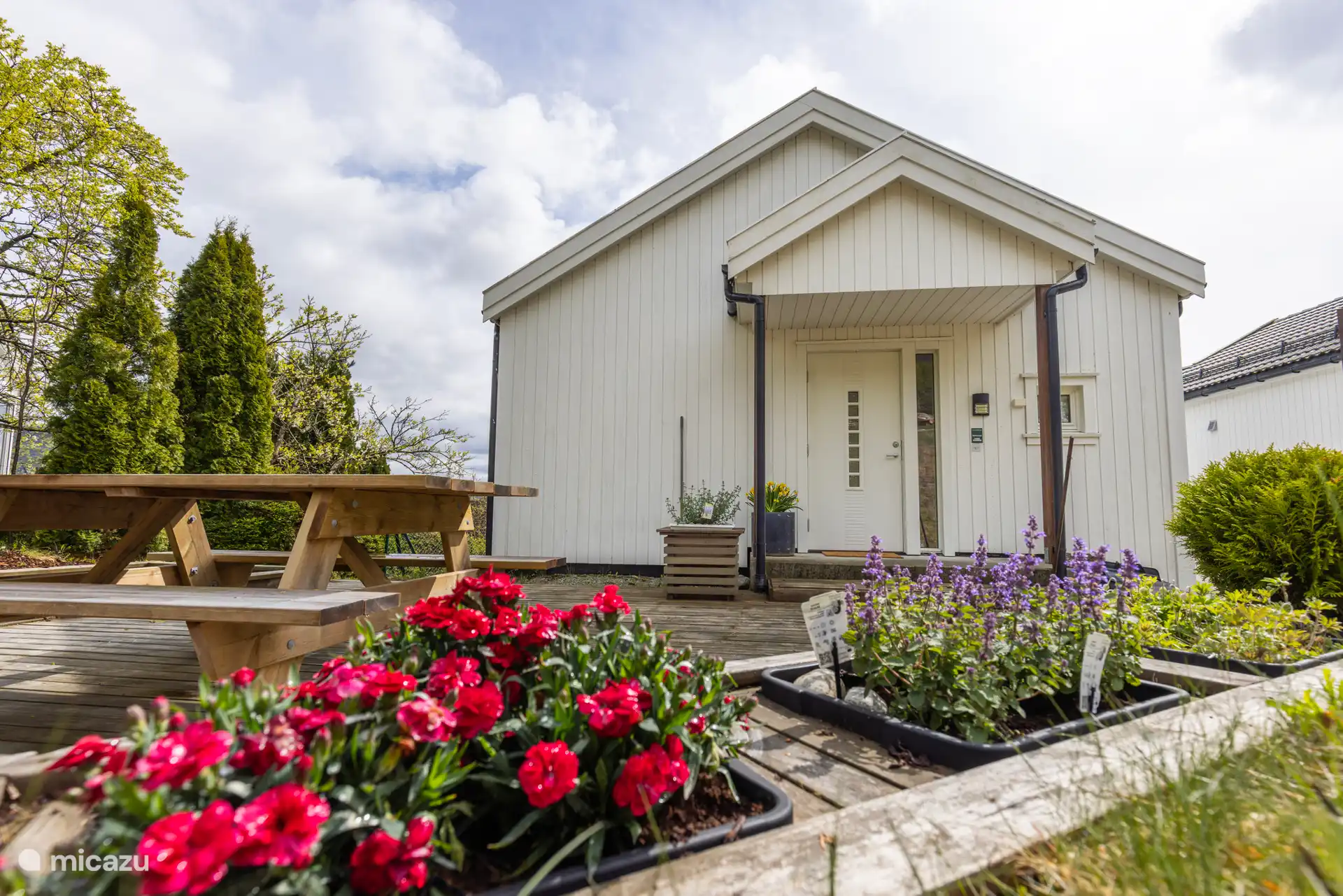 Le jardin privé derrière l’appartement comprend une terrasse avec un coin salon, un barbecue, un bac à sable et un panier à frisbee. 