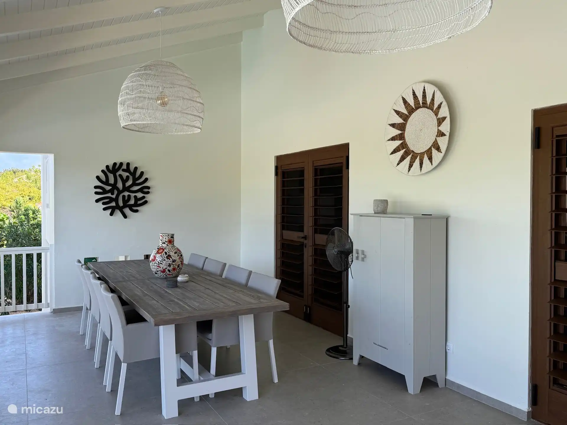 The dining table with 8 comfortable chairs and there are possibly 2 extra, the cupboard with plates and glasses. 