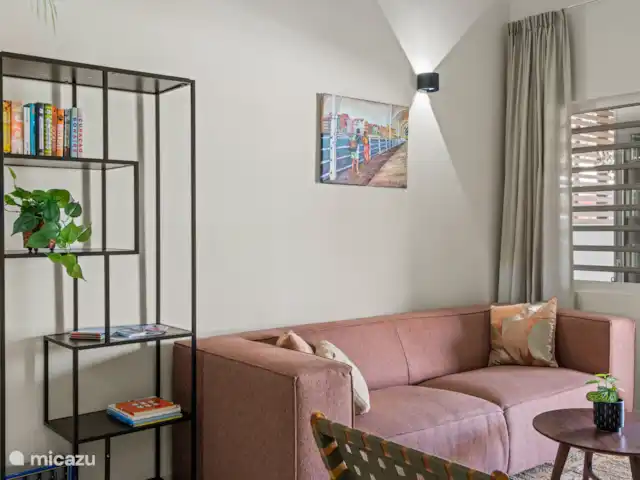 Bunita den Bario Apartments - B | Curaçao, Curaçao-Centre, Willemstad - maison de vacances Salon élégant avec un joli canapé 3 places, une Smart TV et un meuble TV, une étagère avec des livres et des jeux de société.