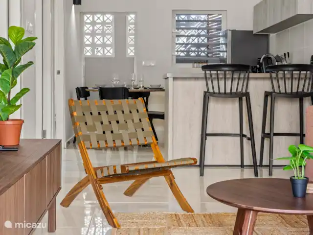 Bunita den Bario Apartments - B | Curaçao, Curaçao-Centre, Willemstad - maison de vacances Salon élégant avec un joli canapé 3 places, une Smart TV et un meuble TV, une étagère avec des livres et des jeux de société.