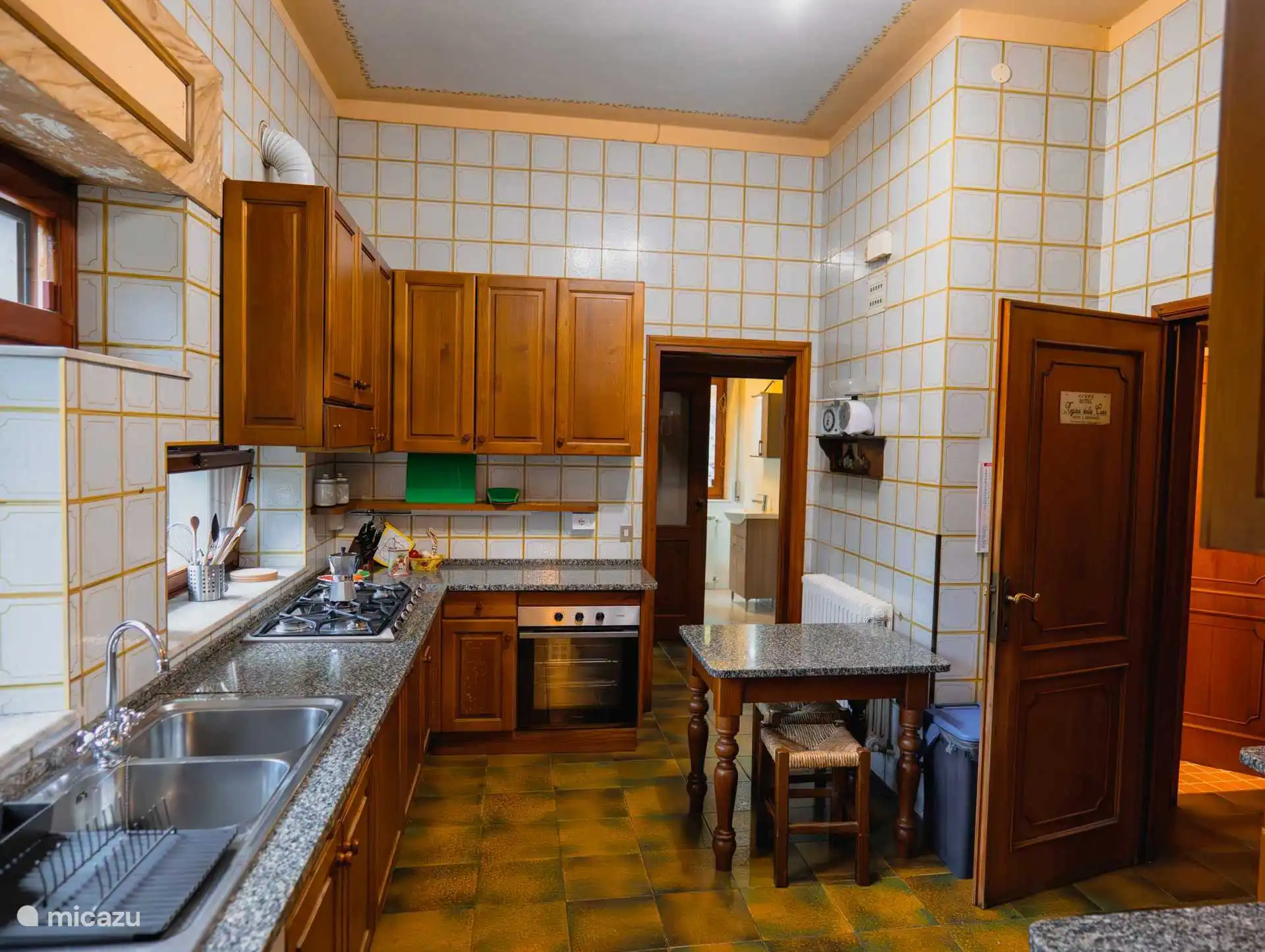 Die vollausgestattete Küche mit Zugang zum Speisezimmer, der Waschküche und der Speisekammer mit Kühlschrank. Gasherd, Spülmaschine, Backofen usw. sind selbstverständlich vorhanden.