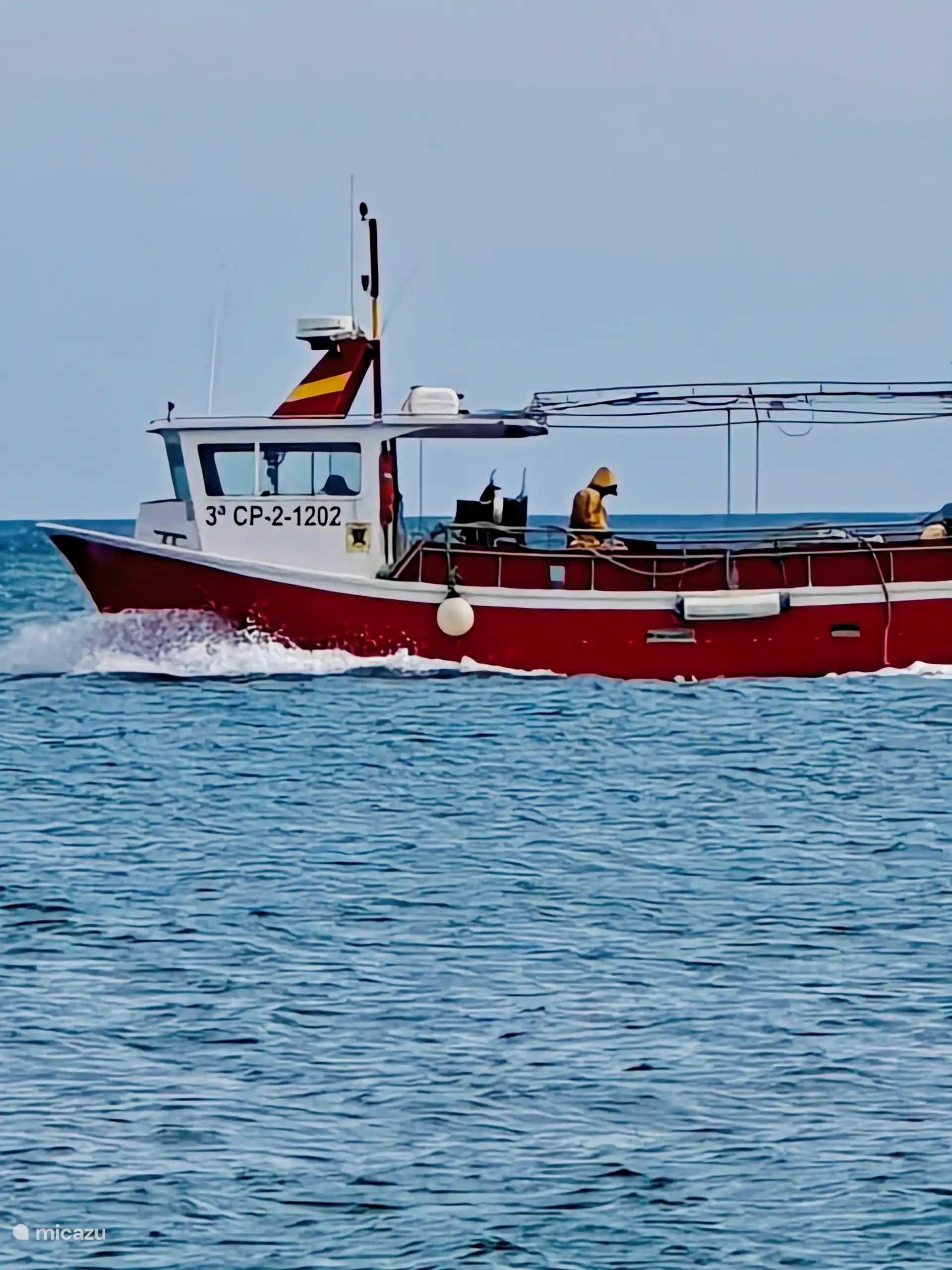 Bateau de pêche passant en mer, vue depuis le balcon.
