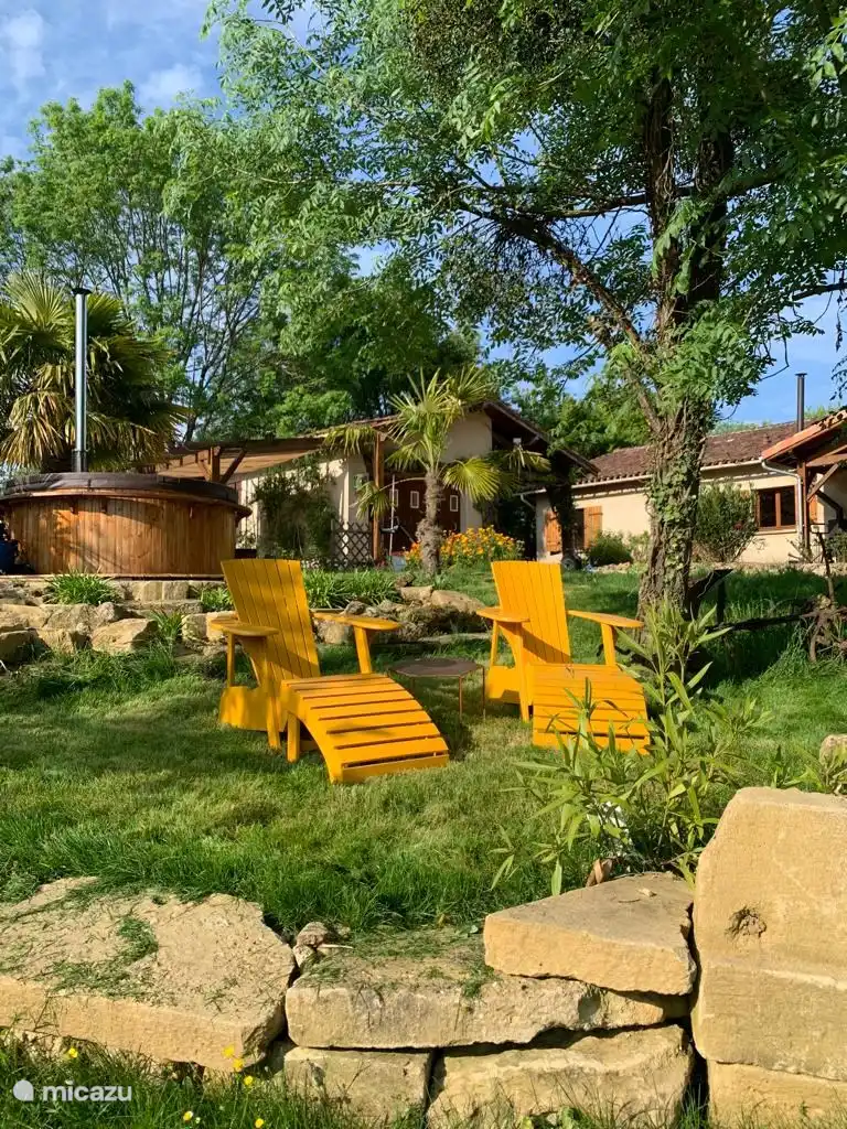 2 Stühle mit schönem Blick auf das Tal. Abends sieht man fast immer Rehe im Tal spazieren. Holzbefeuertes Hottube für 8 Personen im Hintergrund