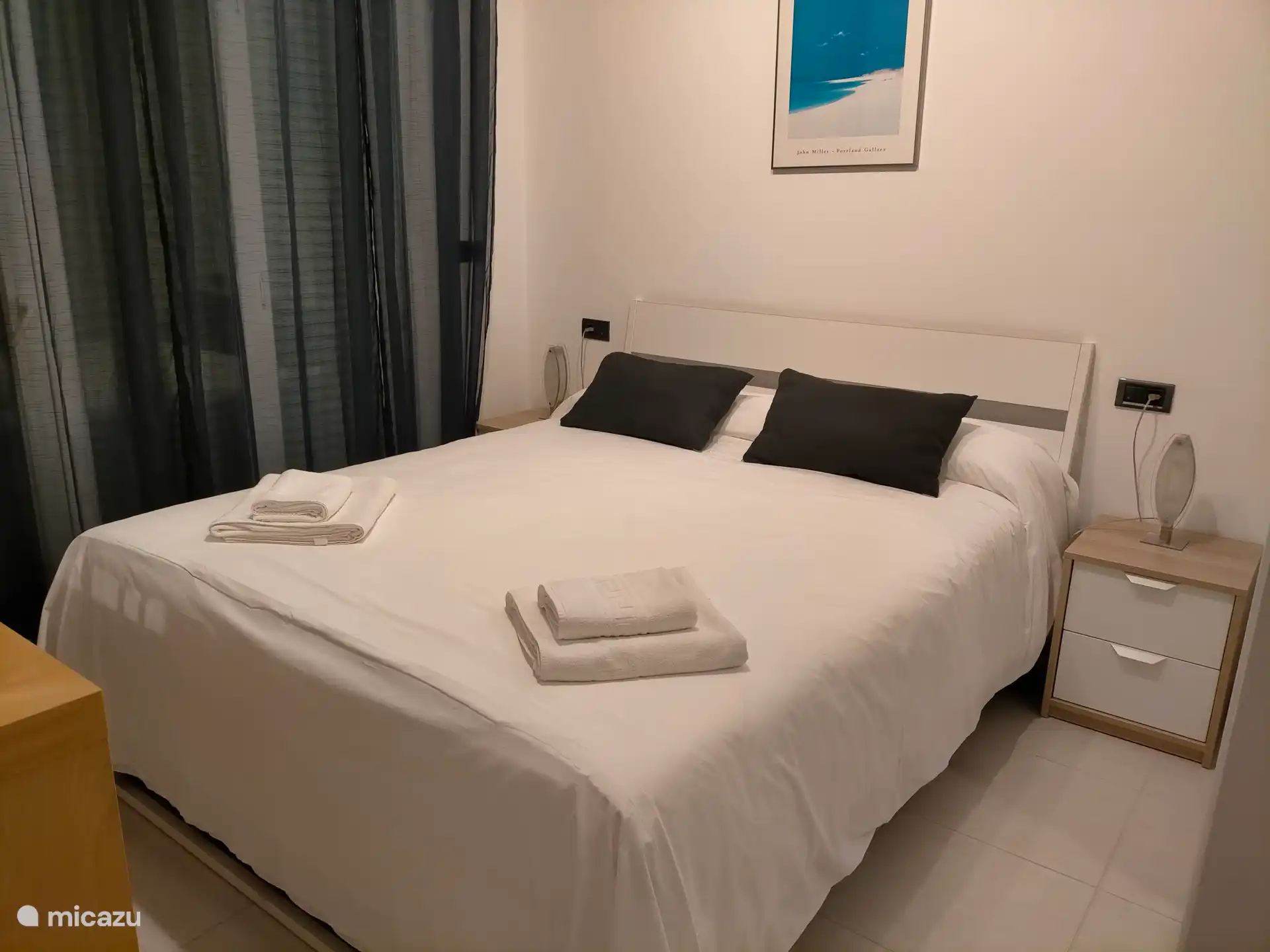 Chambre principale avec lit king size, grande armoire en miroir et portes donnant sur la terrasse.