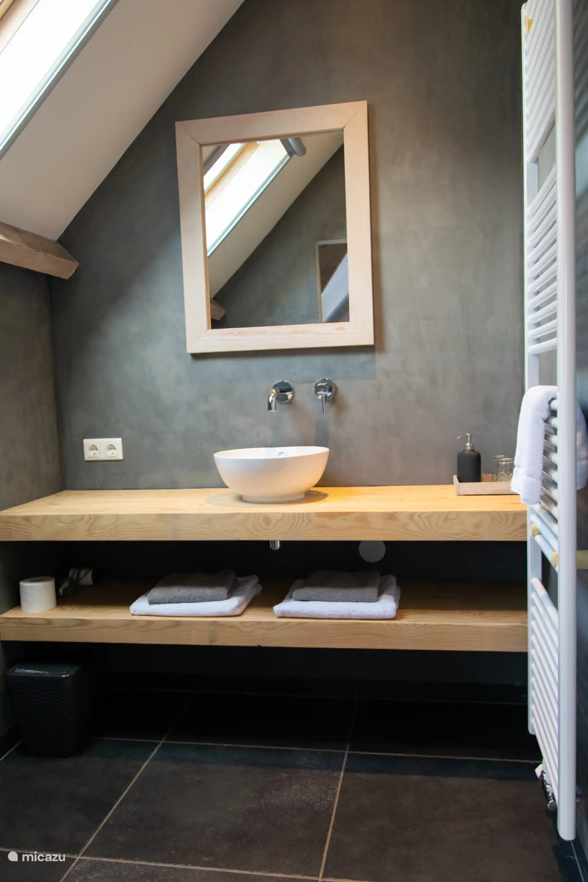 Badezimmer mit geräumiger ebenerdiger Dusche, Waschbecken und WC. 