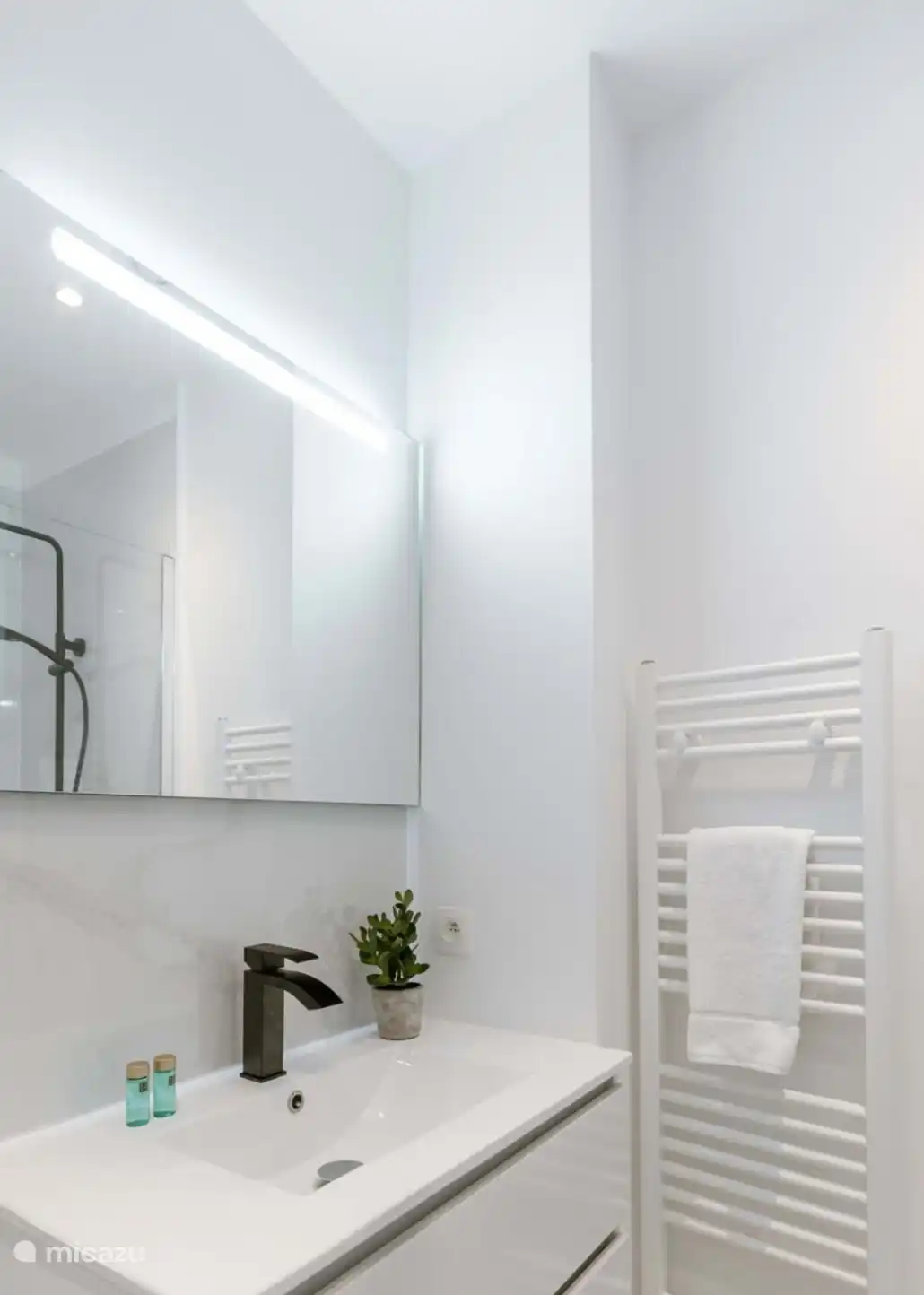 Cuarto de baño con ducha a ras de suelo, secador de pelo y lavabo.