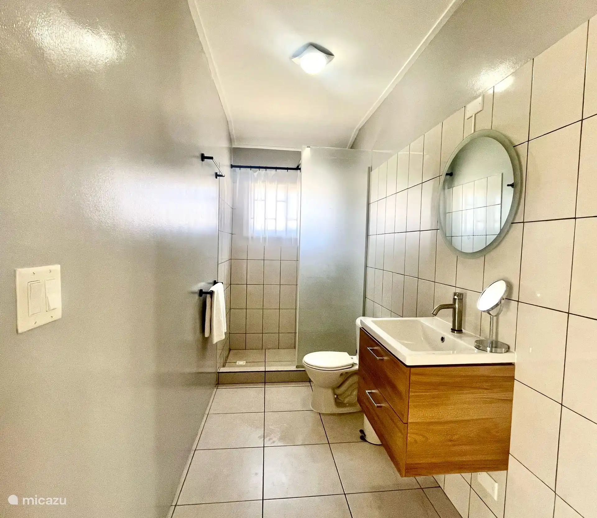 Baño moderno con ducha a ras de suelo y toallas limpias.