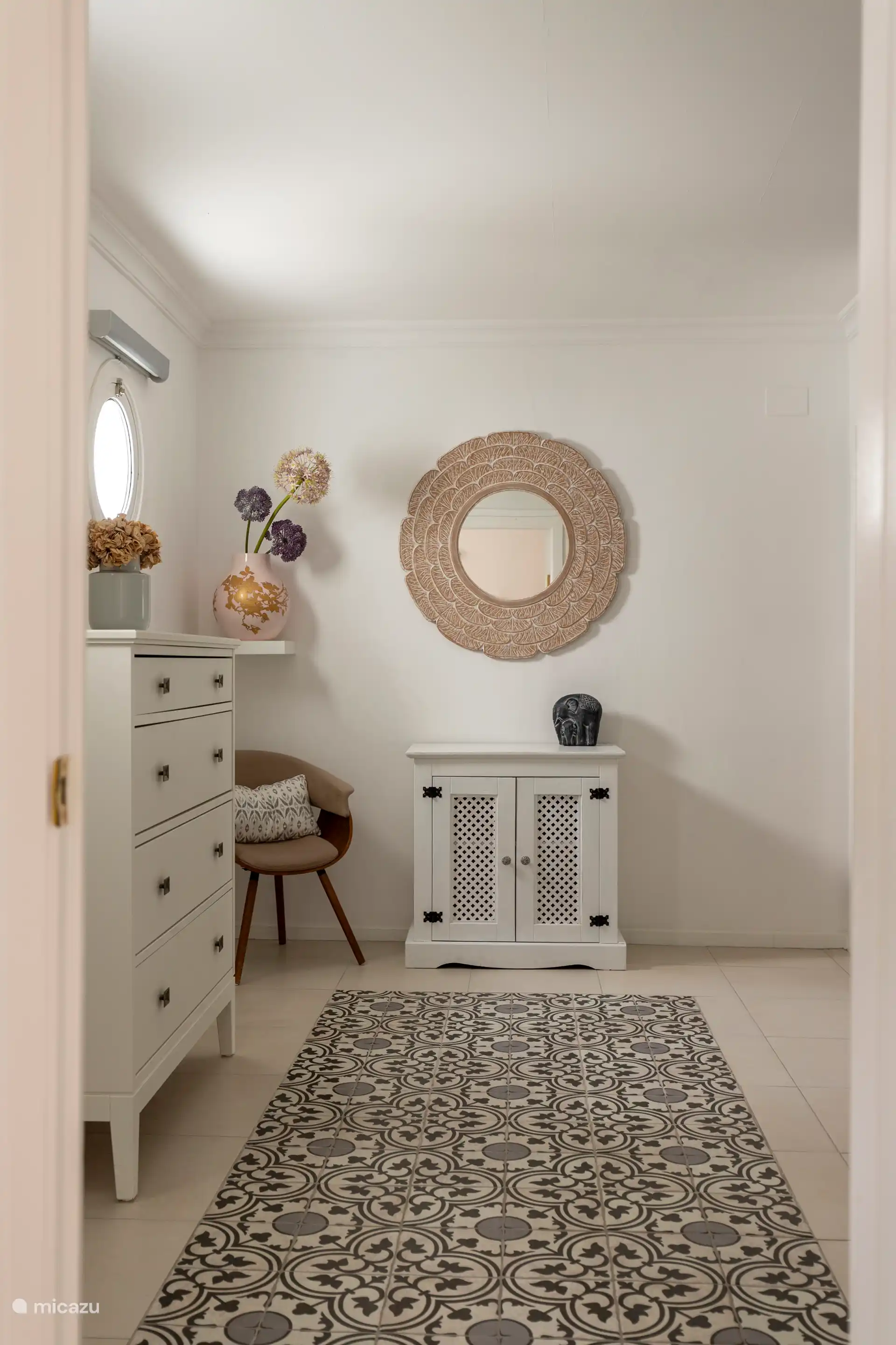 Chambre spacieuse avec lit double, tables de chevet, commode, chaise, miroir et peignoirs.