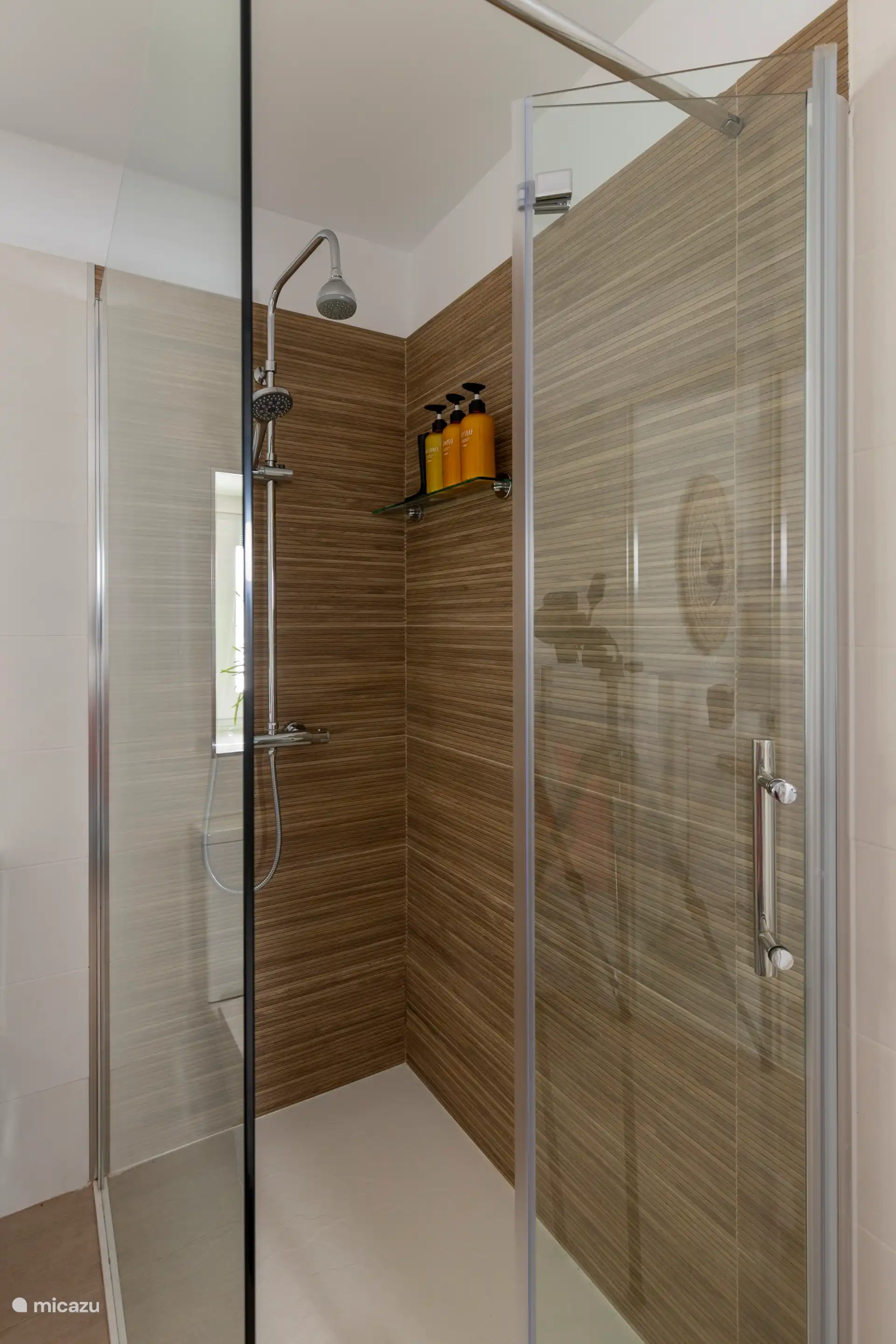 Salle de bain spacieuse et moderne avec douche à l’italienne, toilettes, lavabo, miroir, chauffage des serviettes et articles de toilette.