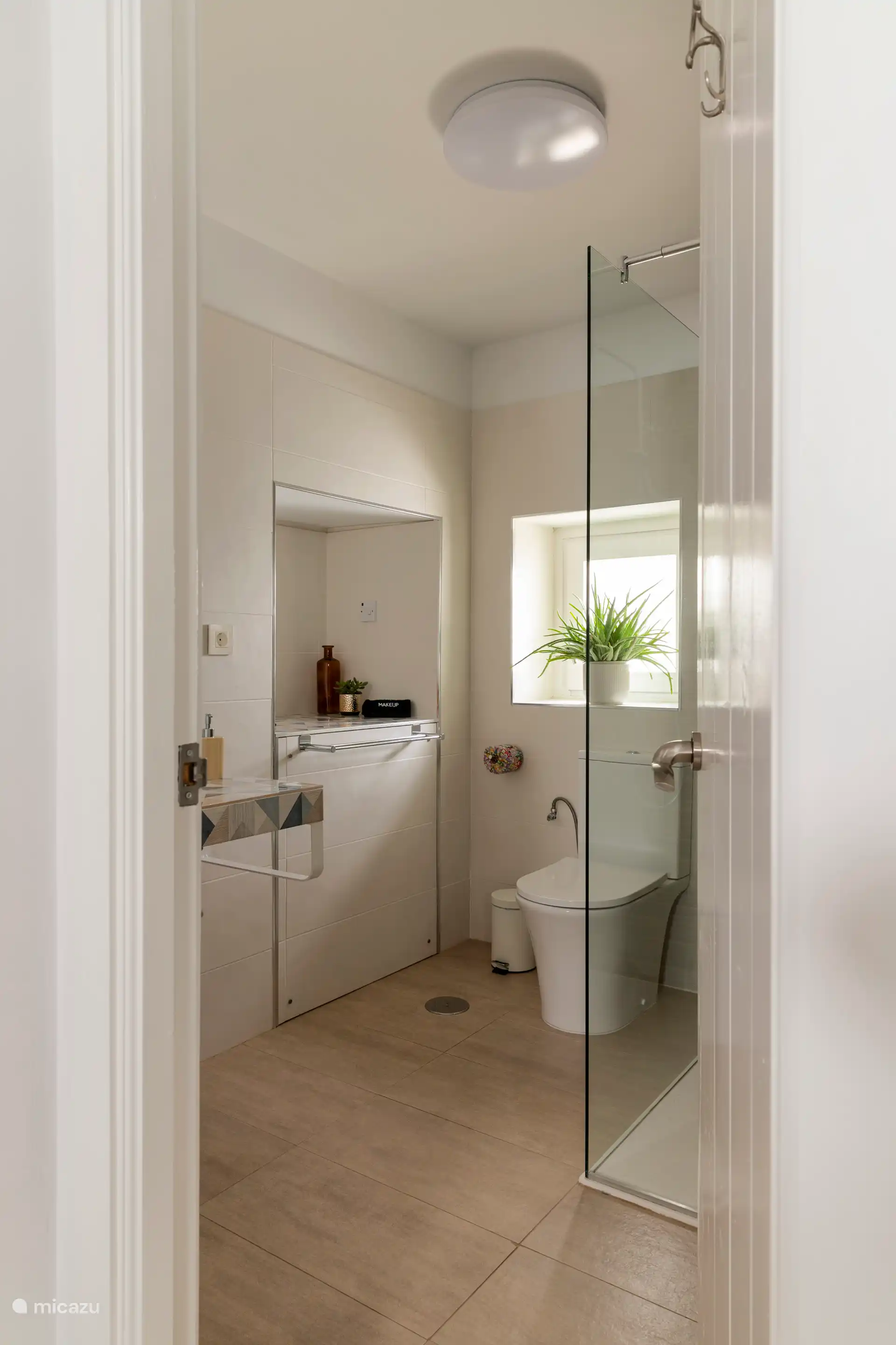 Salle de bain spacieuse et moderne avec douche à l’italienne, toilettes, lavabo, miroir, chauffage des serviettes et articles de toilette.