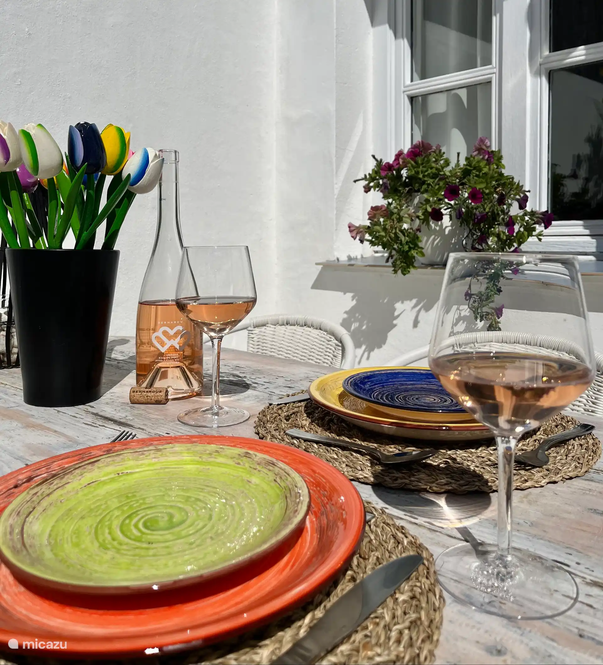 Terrasse privée avec table avec 4 chaises, chaise confortable, parasol, plantes et corde à linge. 