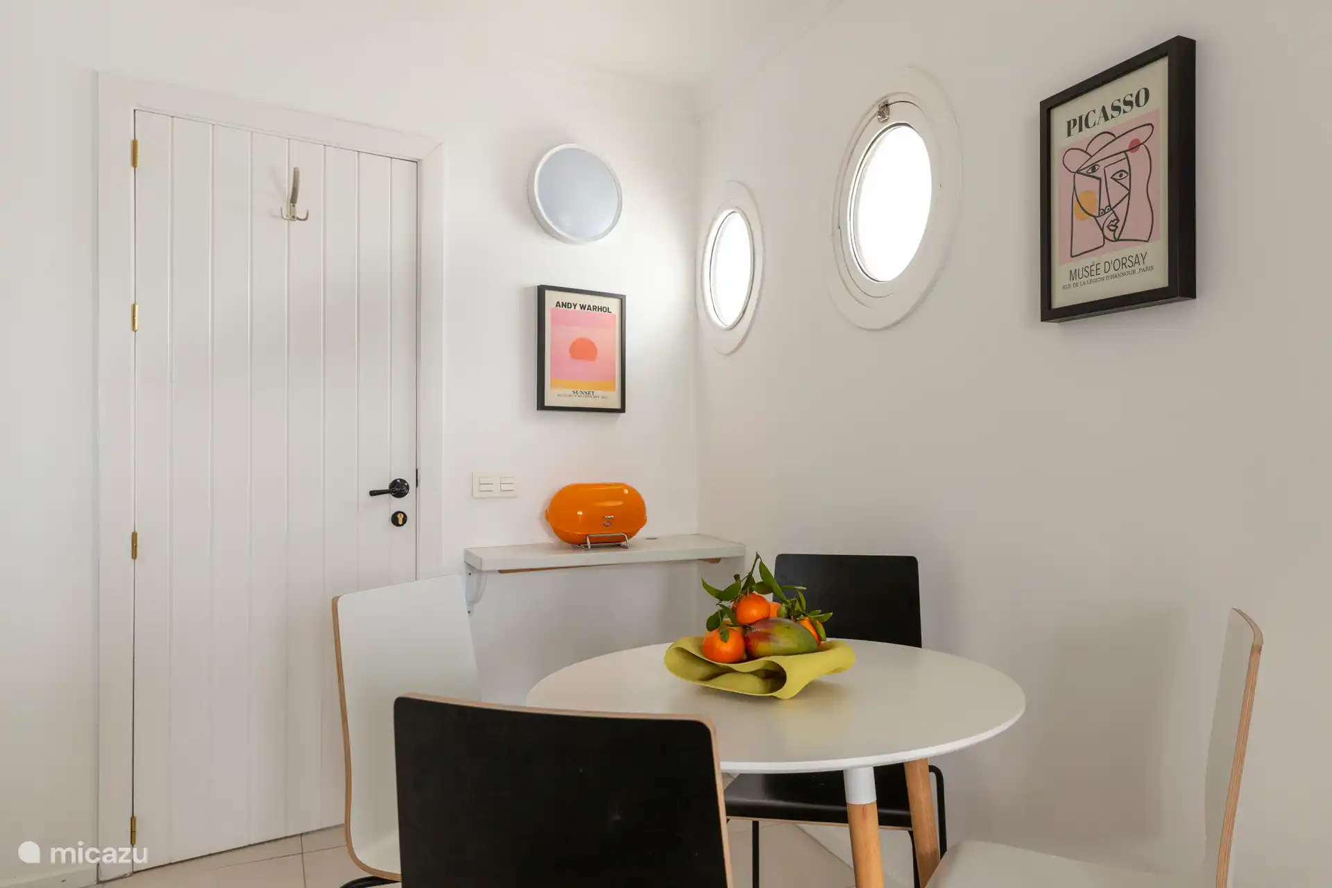 Cuisine entièrement équipée avec un réfrigérateur, un micro-ondes/grill, une plaque à induction, une machine à café Nespresso, un grille-pain SMEG, une bouilloire et une table avec quatre chaises.