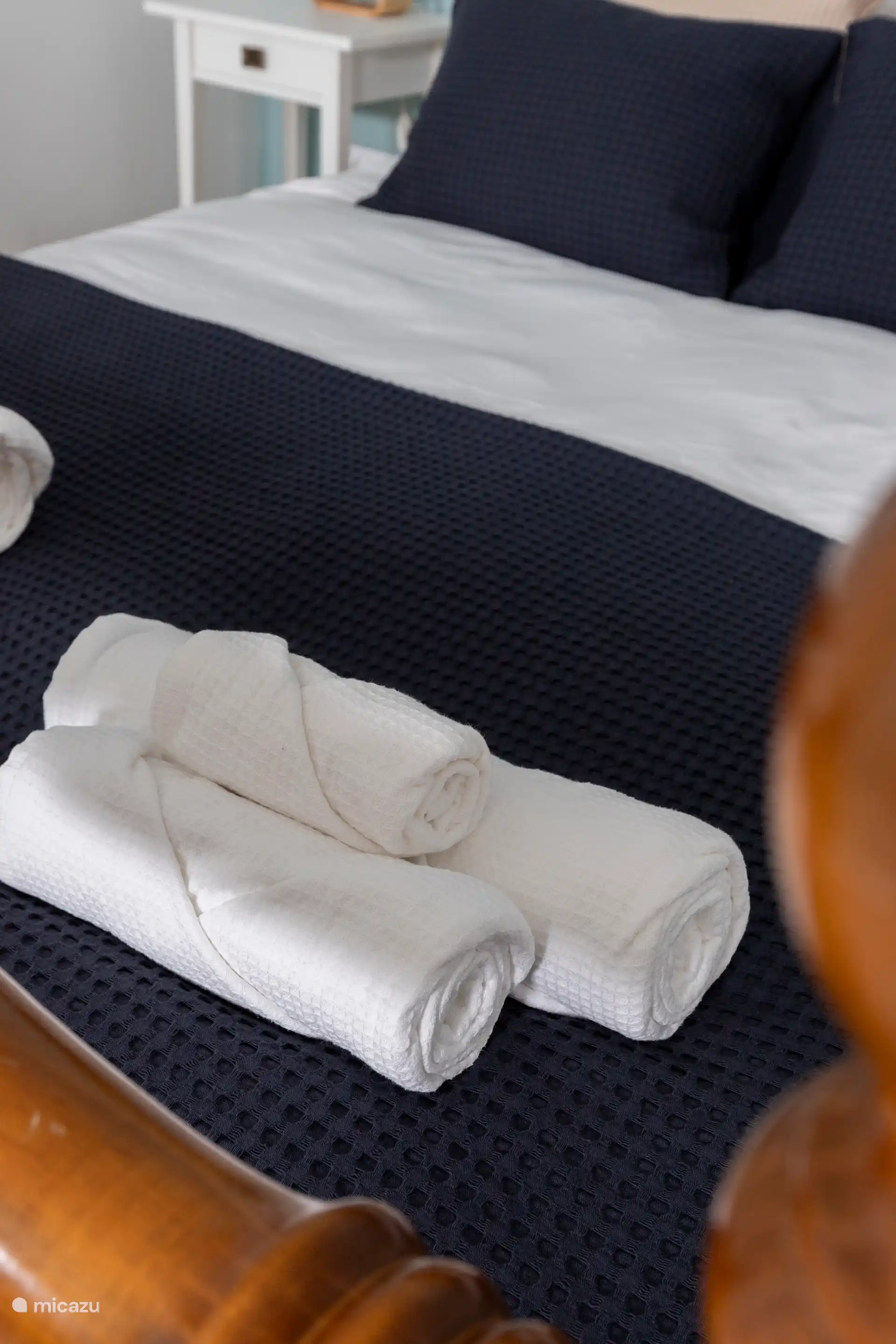 Chambre spacieuse avec lit double, serviettes, tables de chevet, commode, chaise, miroir et peignoirs.