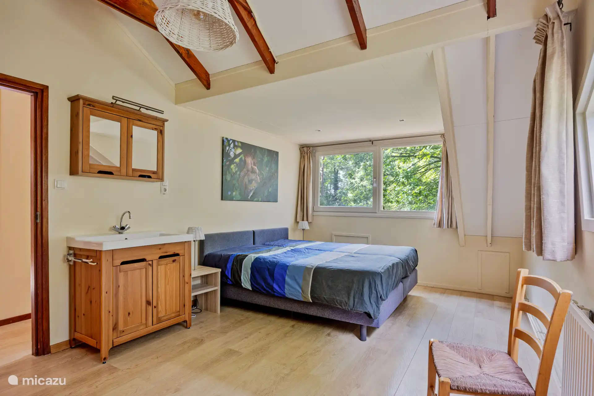 Ruime slaapkamer met twee geschakelde boxspring bedden en wasbak.