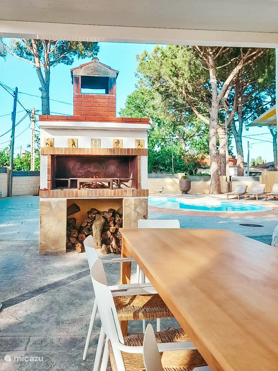 Der lange Tisch unter dem Baldachin mit dem holzbefeuerten Grill