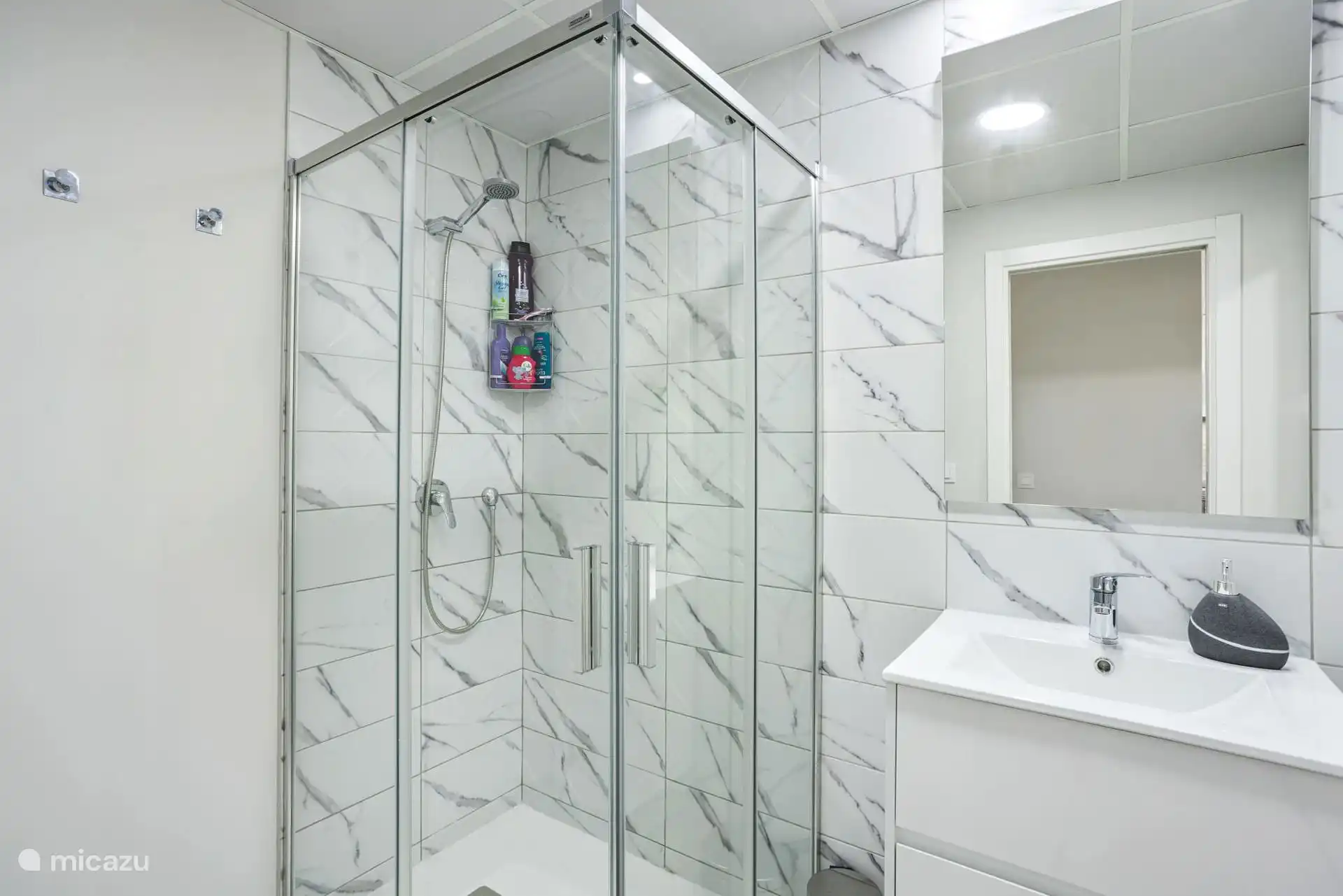 Das Badezimmer mit ebenerdiger Dusche, Waschbecken und separatem WC