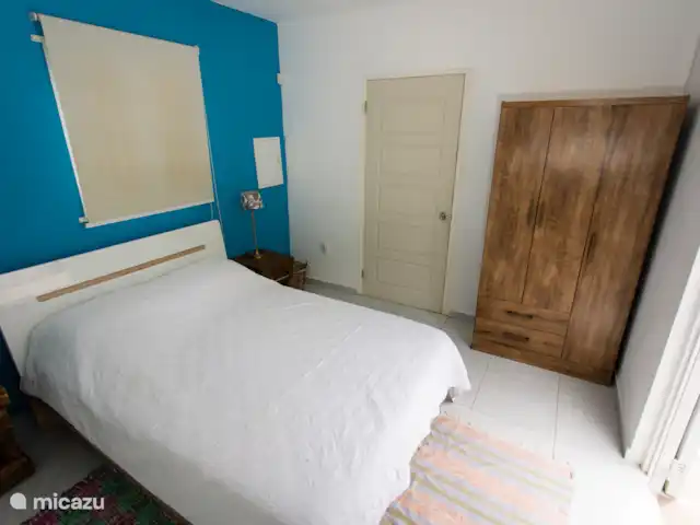 Studio Nature au bord de la piscine – Westpunt Es | Curaçao, Banda Abou (ouest), Westpunt - appartement Angle alternatif de la chambre montrant une grande armoire en bois et un mur d’accent turquoise vif.