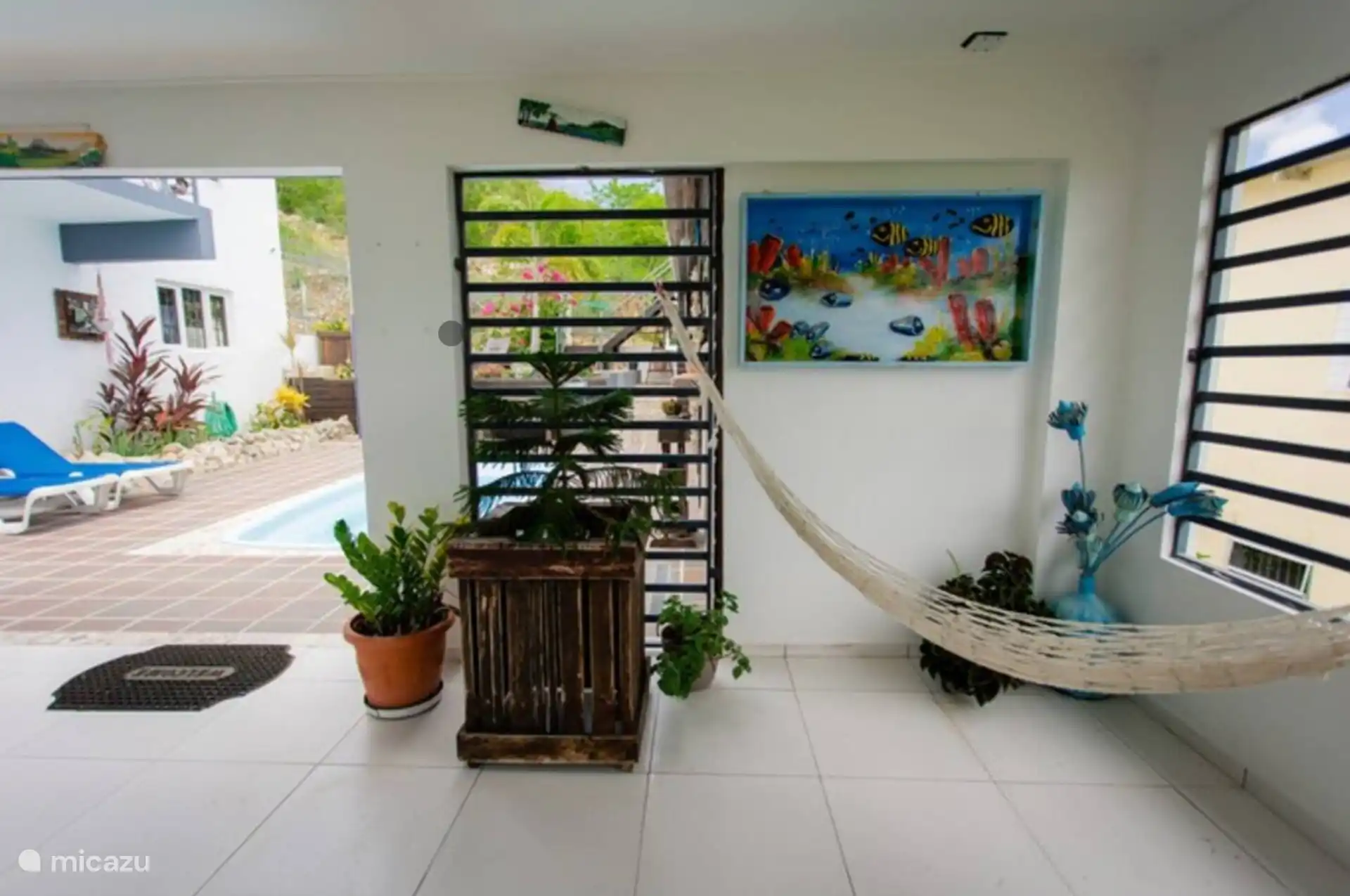 Entspannen Sie sich mit einer Hängematte, Pflanzen und Kunstwerken, die von der Unterwasserwelt Curaçaos inspiriert sind. Ein gemütlicher, schattiger Bereich zum Entspannen.