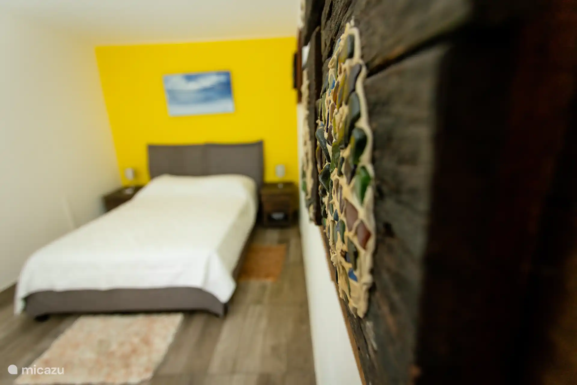 Künstlerische Details treffen im Schlafzimmer auf Komfort mit Wandkunst zum Thema Insel und natürlichen Akzenten.