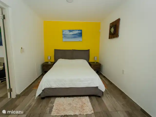 Escapade dans les Caraïbes 1 chambre  | Curaçao, Banda Abou (ouest), Westpunt - appartement Lit queen-size confortable avec des tables de chevet, des lampes et un mur d’accent.