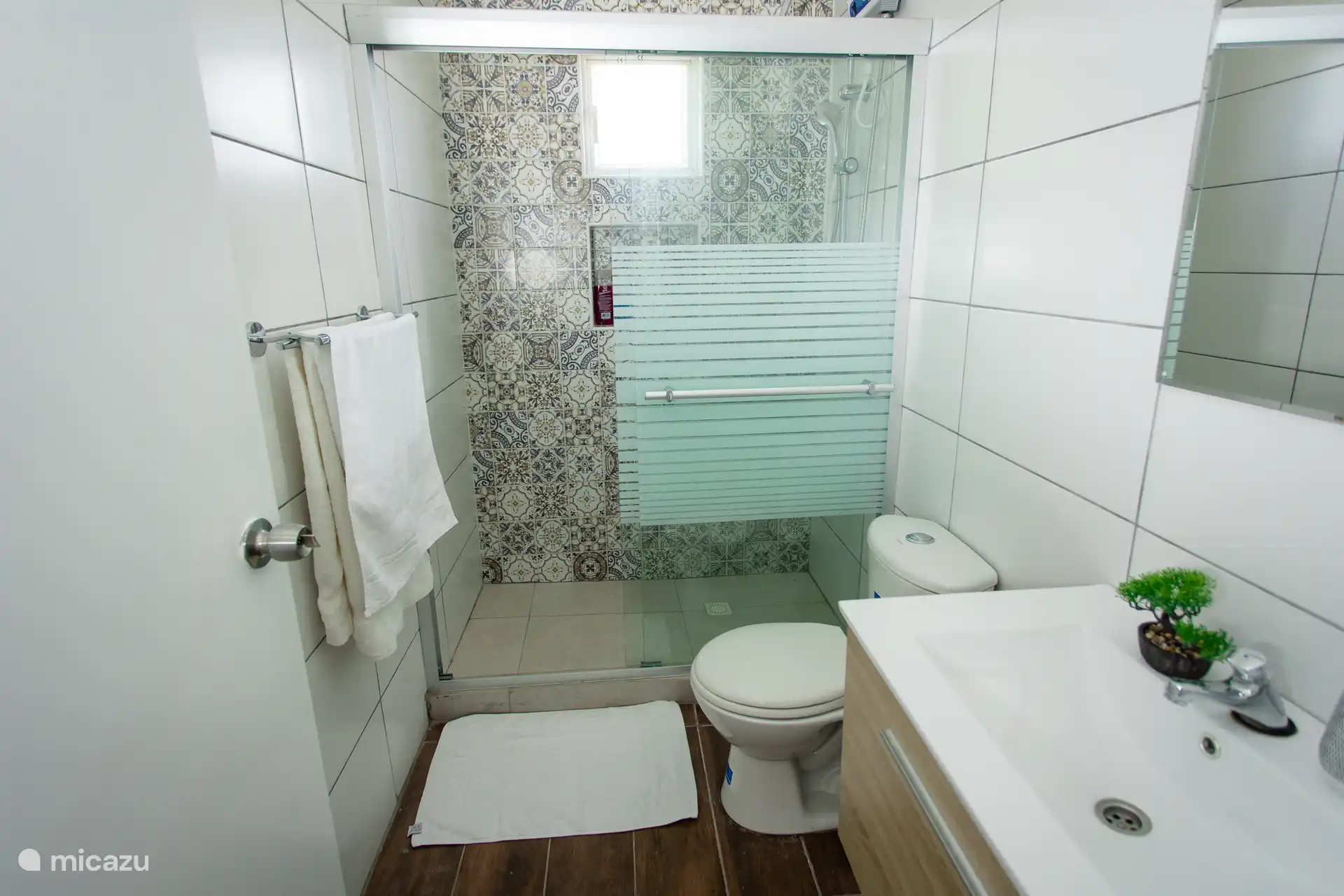 Spacious walk-in shower with decorative tiling, frosted glass, and clean amenities.