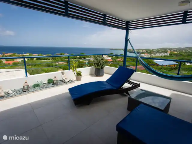 Retraite avec vue sur l’océan tropical | Curaçao, Banda Abou (ouest), Westpunt - appartement Un coin salon ombragé avec des transats et un hamac surplombant la mer et les collines verdoyantes.
