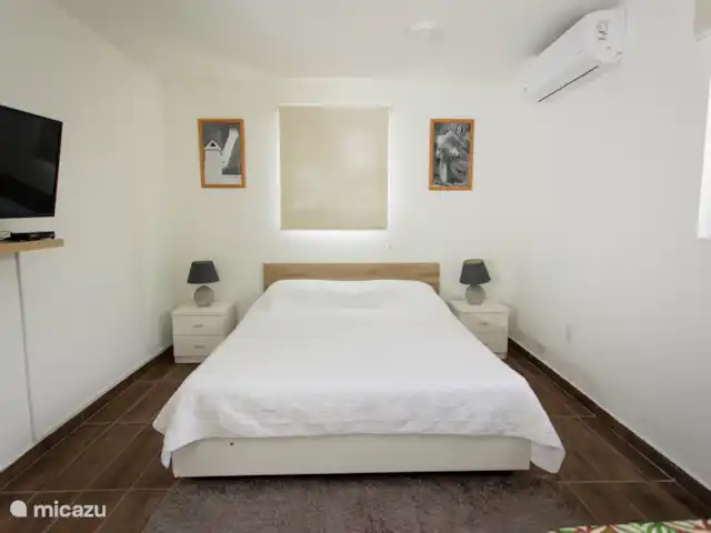 Retraite avec vue sur l’océan tropical | Curaçao, Banda Abou (ouest), Westpunt - appartement Chambre confortable avec grand lit, climatisation, tables de chevet et lumière naturelle à travers les fenêtres.