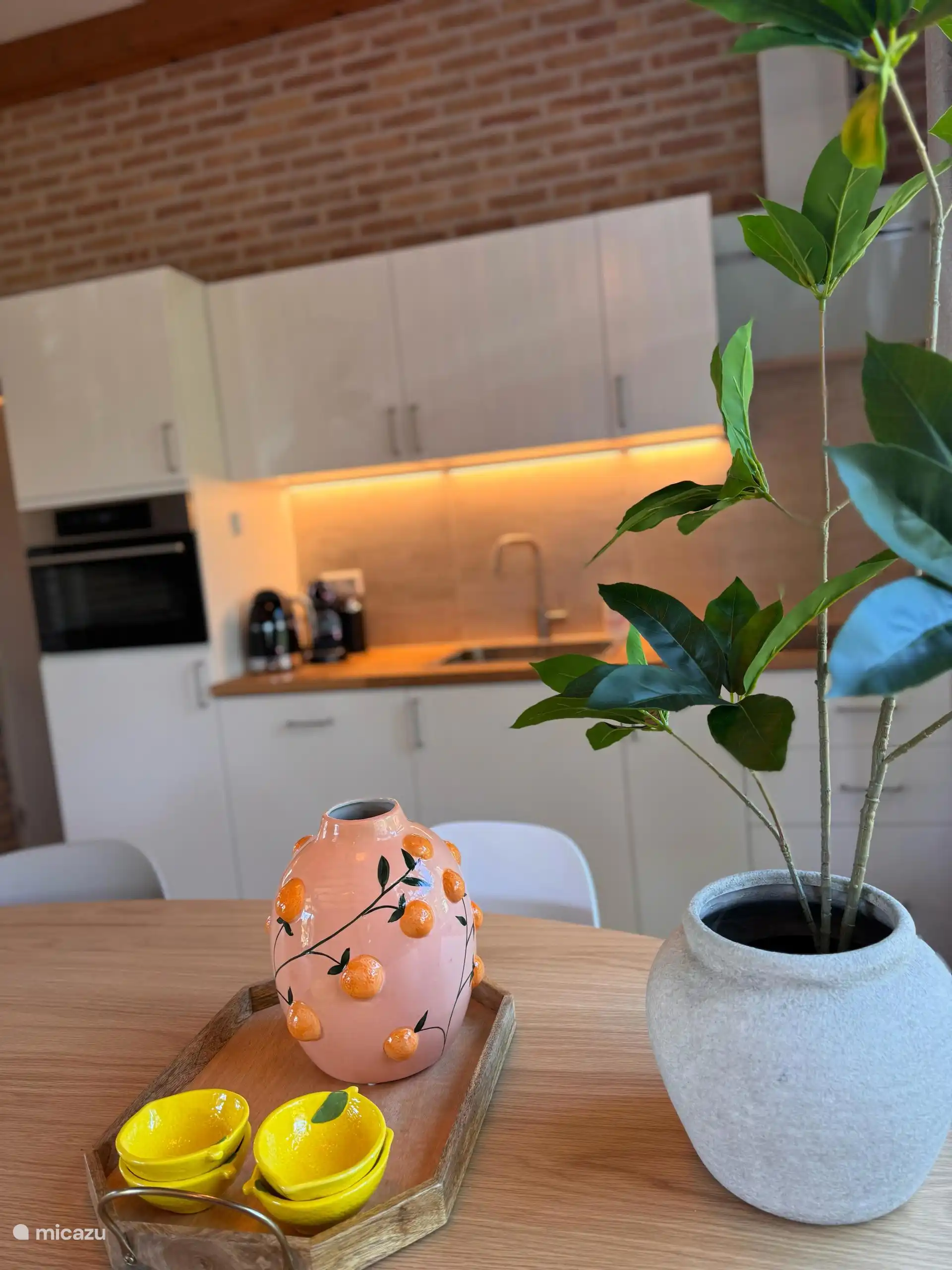 Ein stimmungsvolles Detail: orangefarbene Akzente, grüne Pflanzen und eine Küche, die zum gemeinsamen Kochen und Essen einlädt.