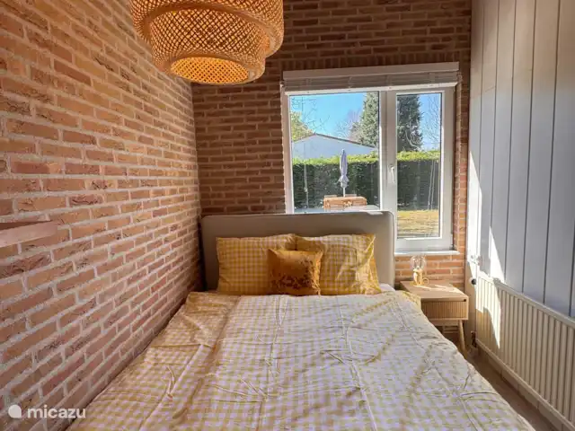 Villa Frans | Pays-Bas, Zélande, Renesse - maison de vacances Coin chambre confortable avec literie jaune et blanche, vue sur la verdure et un doux soleil matinal. Dormez bien en Zélande !
