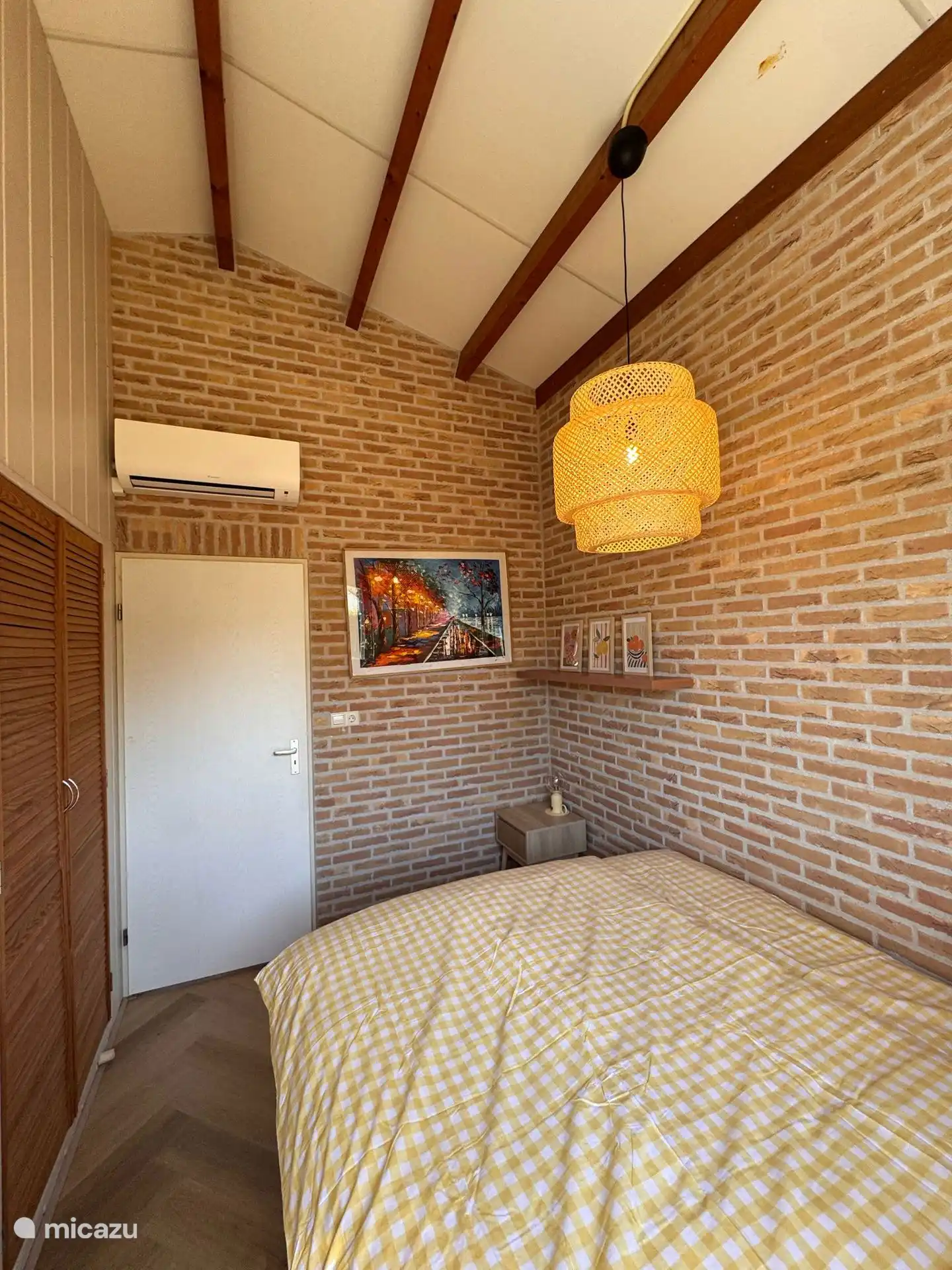 Warme Backsteinwände, ein fröhliches Kunstwerk, eine schöne Klimaanlage und ein großer Einbauschrank runden es ab.