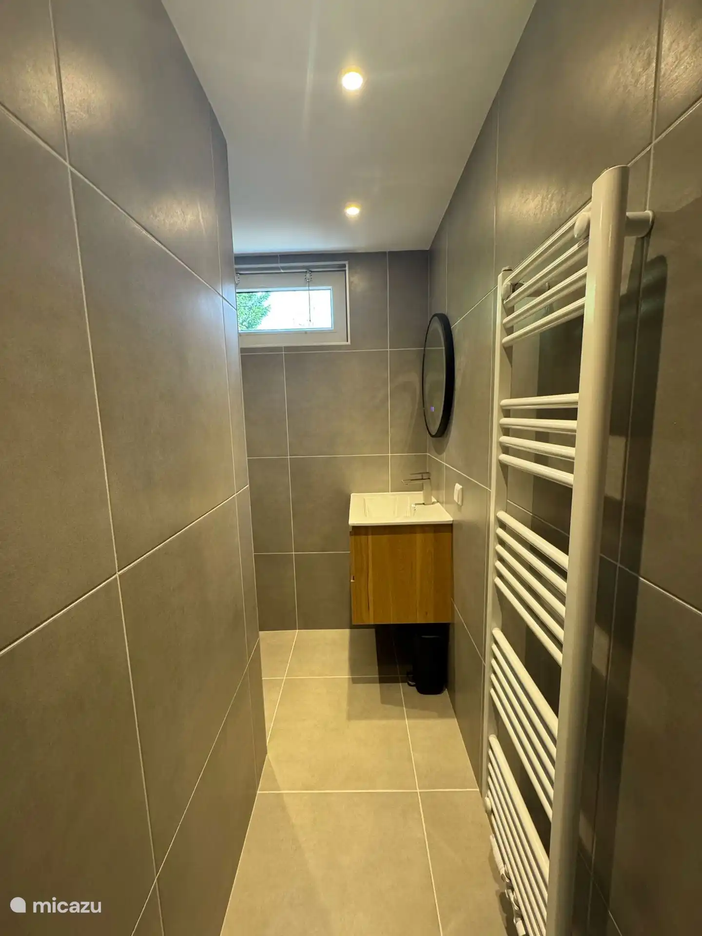 Klare Linien, Holzmöbel und ein runder Spiegel sorgen für einen modernen, frischen Look im Badezimmer.