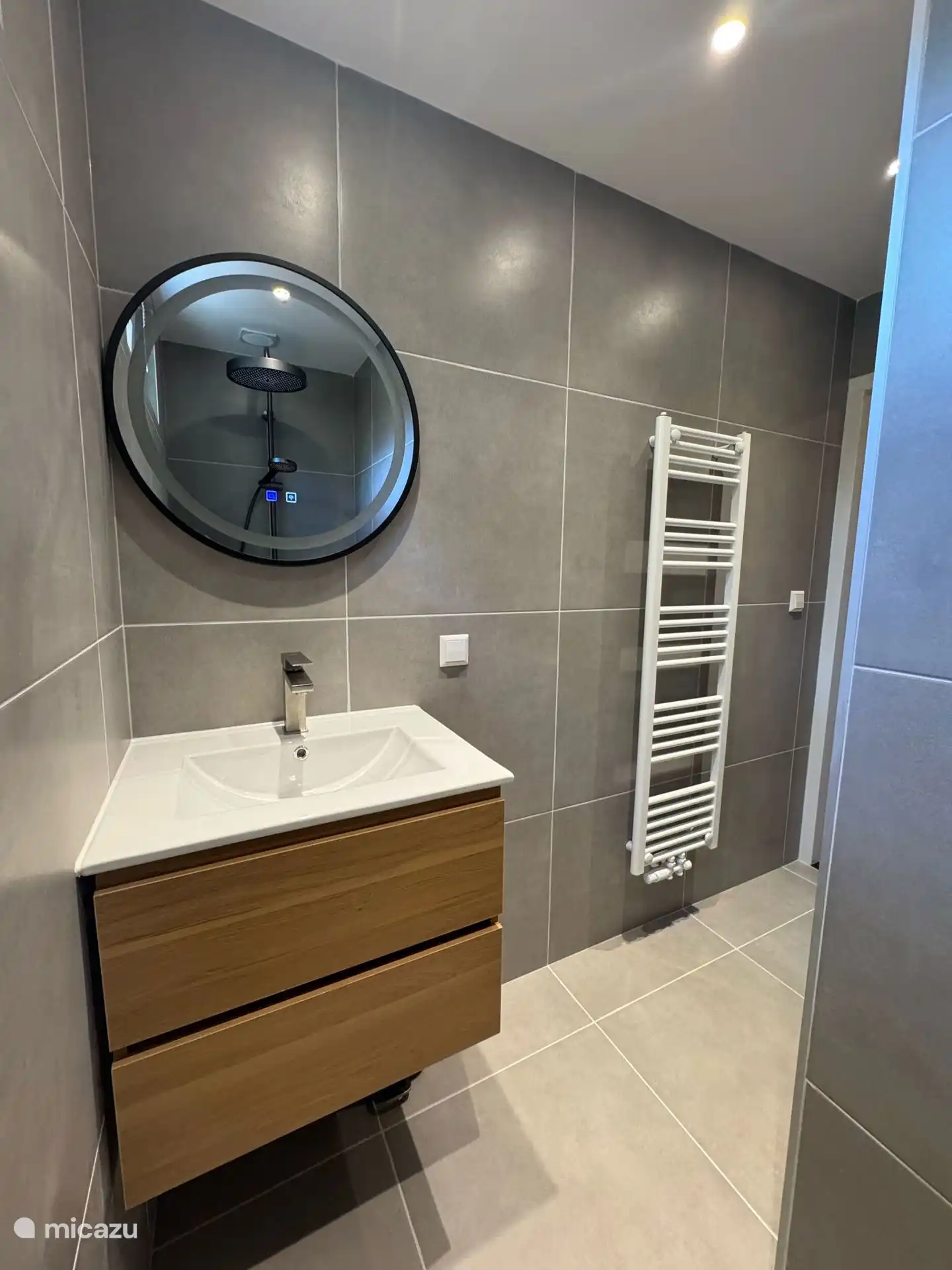 Badezimmer mit Design-Heizkörper, großen Fliesen und luxuriösen Oberflächen. Komfort und Stil kommen hier perfekt zusammen.