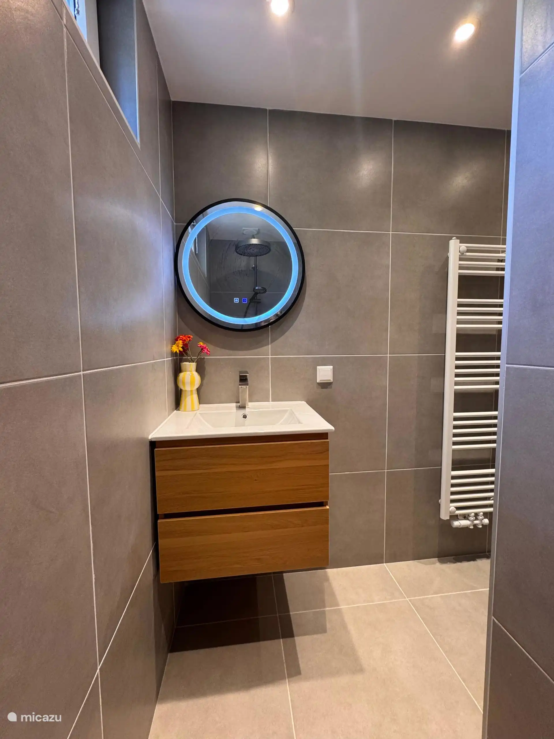 Schlankes Waschbecken mit rundem Spiegel und einer fröhlichen Vase. Kleines Detail, großer Unterschied!