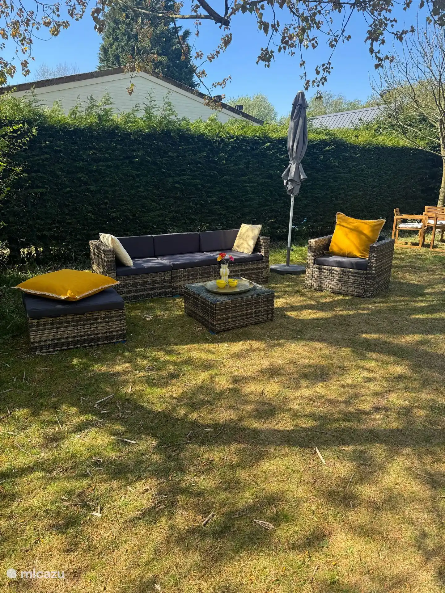 Loungebereich mit bunten Kissen und Sonnenschirm. Perfekt für entspannende Momente im Garten.