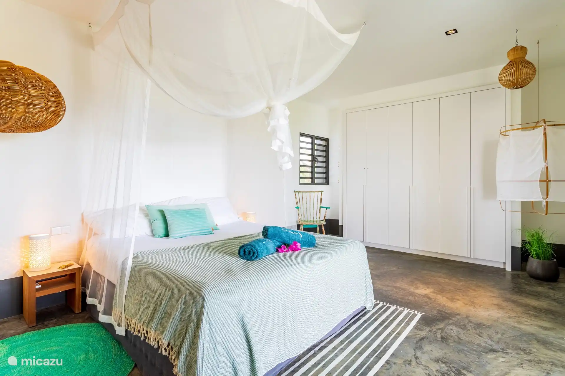The third bedroom on the first floor features a king-size bed with mosquito net and AC. This room has access to the large balcony at the rear with a view of the garden and the swimming pool.